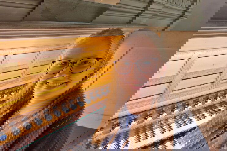 Eine weiblich gelesene, junge Frau mit Brille sitzt an einer Orgel.