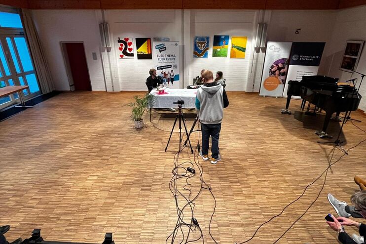 Zwischen zwei Tischen liegen Kabel, auf den Tischen Mikros und Laptops und technische Geräte.