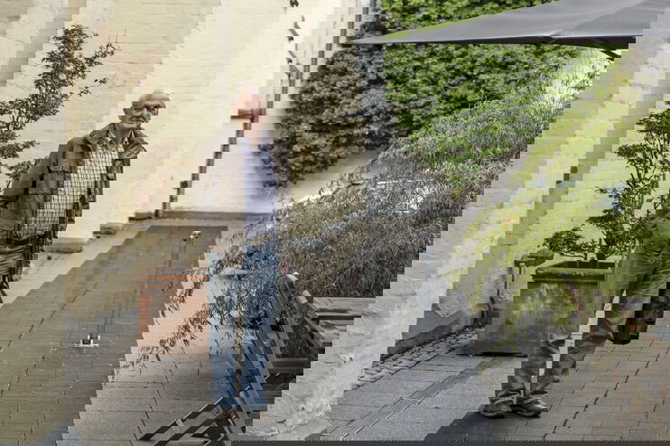 Eine als Mann lesbare Person im Innenhof eines Hotels.