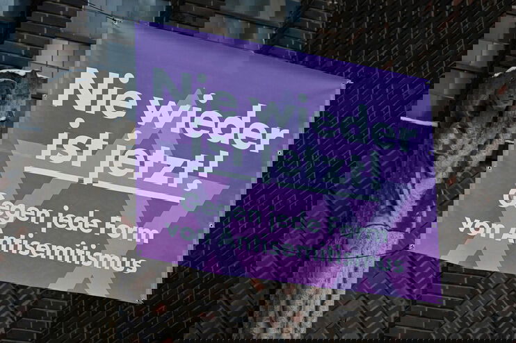 Banner mit der Aufschrift "Nie wieder ist jetzt! Gegen jede Form von Antisemitismus" an einer Kirche