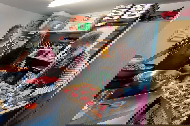 Drei weiblich gelesene Personen richten Desserts auf einem Servierwagen an.