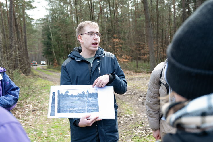 Mehrere junge Menschen stehen um eine Person, die ein schwarz-weißes Foto zeigt.