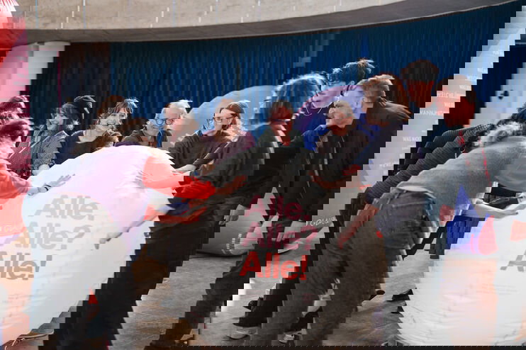 Mehrere Personen rollen einen großen Ball mit der Aufschrift: Alle. Alle? Alle!