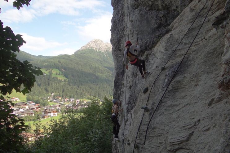 Eine Person klettert an einem rauen Felsen.