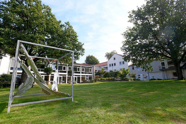 Ein Tagungshaus mit einer Wiese und einem Kunstwerk im Vordergrund.