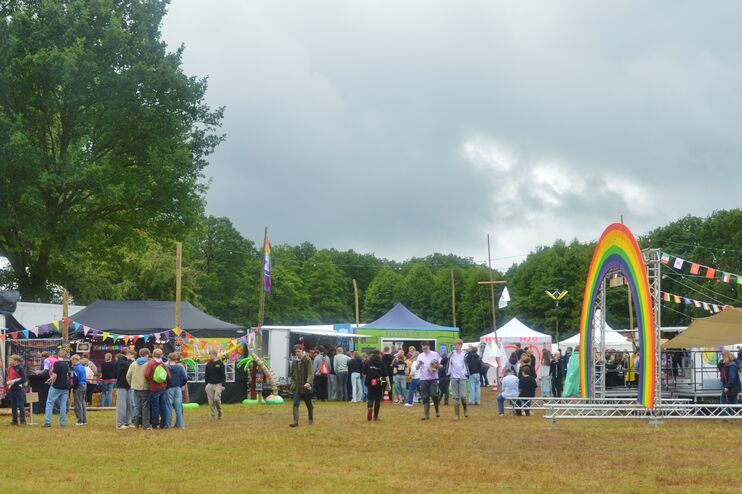 Eine Zeltstadt mit vielen jungen Menschen und einem großen Regenbogen.