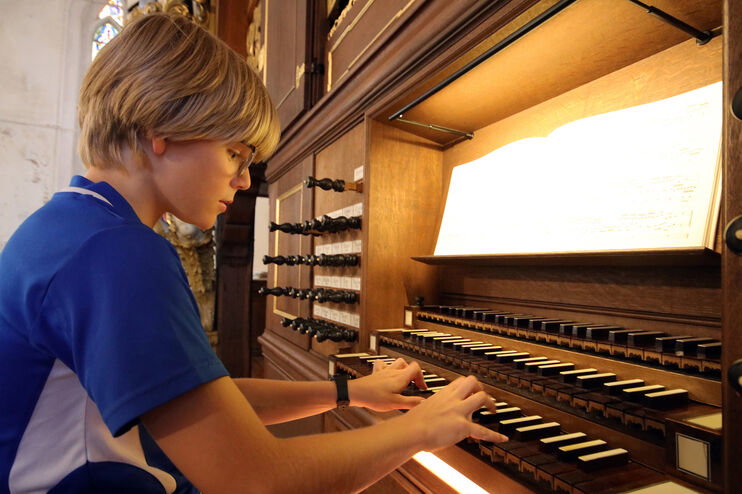 Eine als Junge lesbare Person spielt auf einer Orgel.