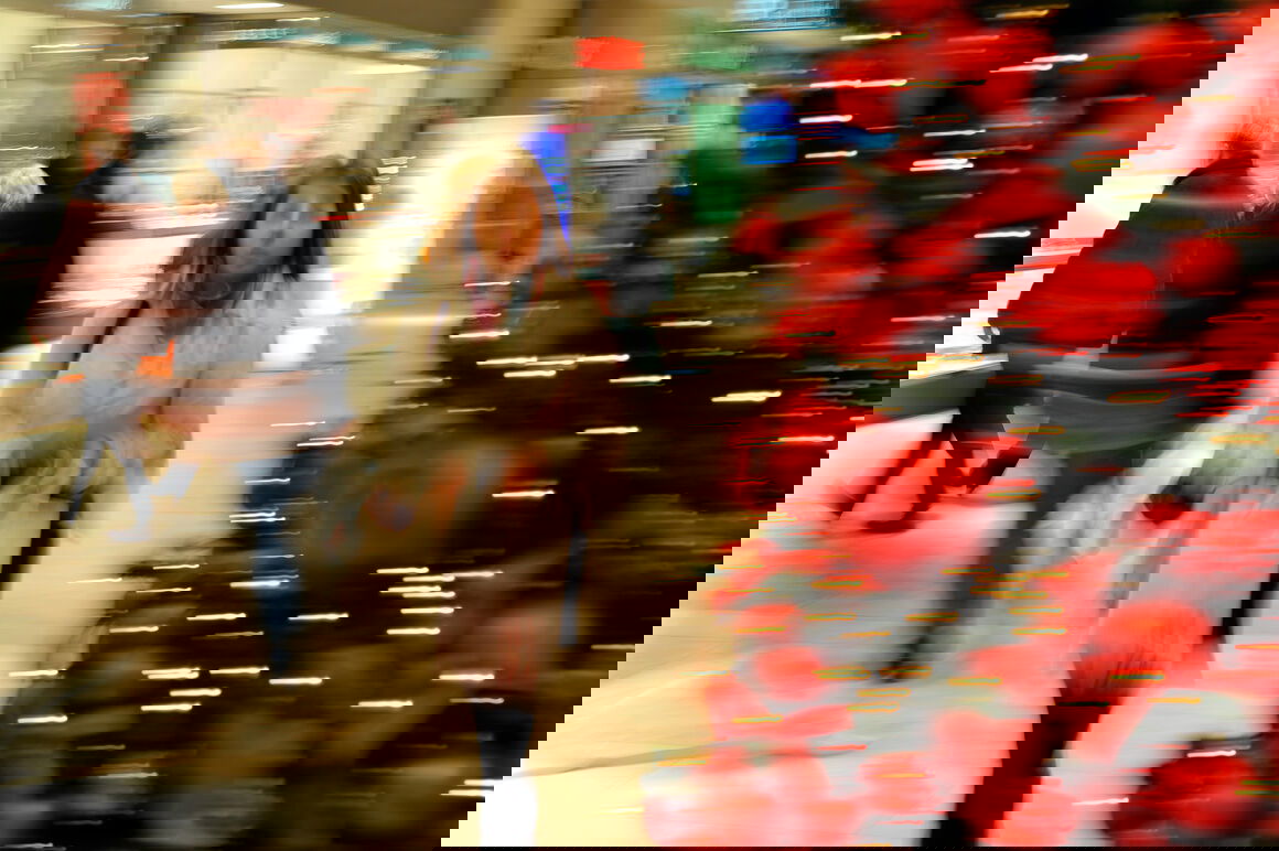 Eine als Frau lesbare Person geht an einem geschmückten Weihnachtsbaum vorbei.