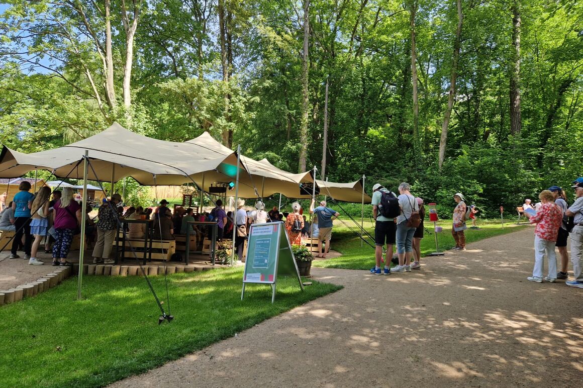 Ein großes Zeltdach im Grünen, besucht von mehreren Menschen