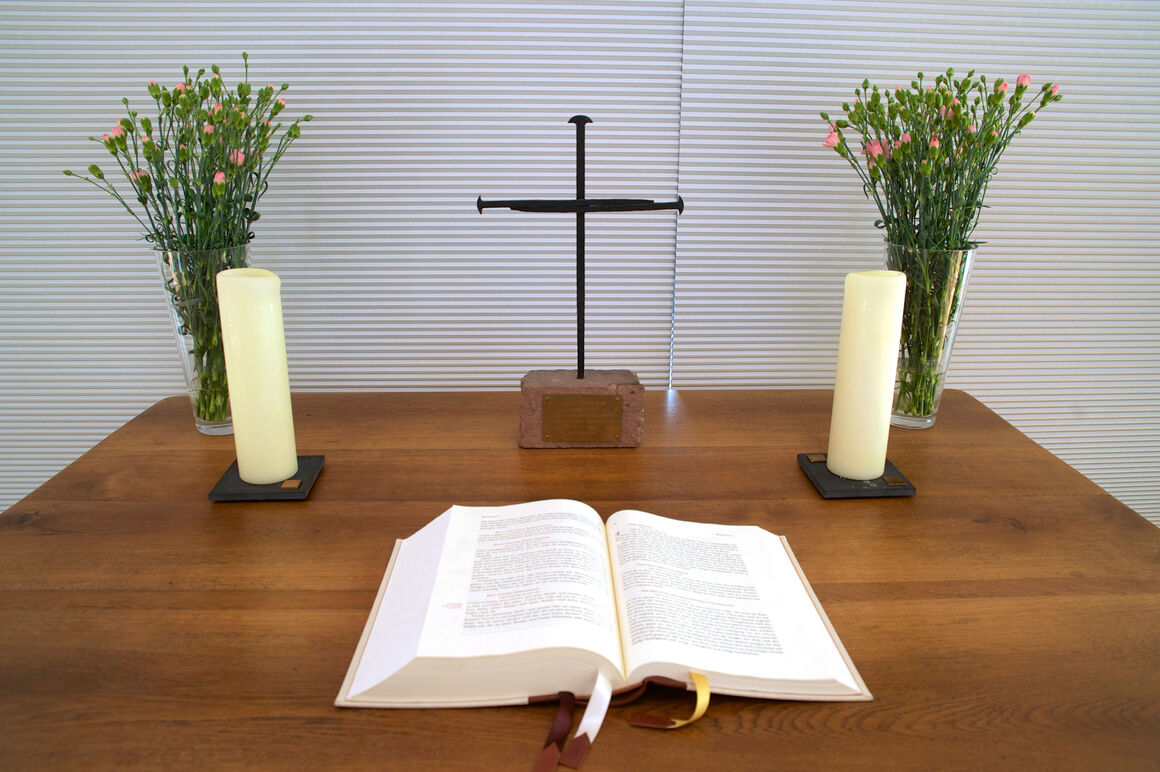 Ein Nagelkreuz auf einem Alter hinter einer aufgeschlagenen Bibel