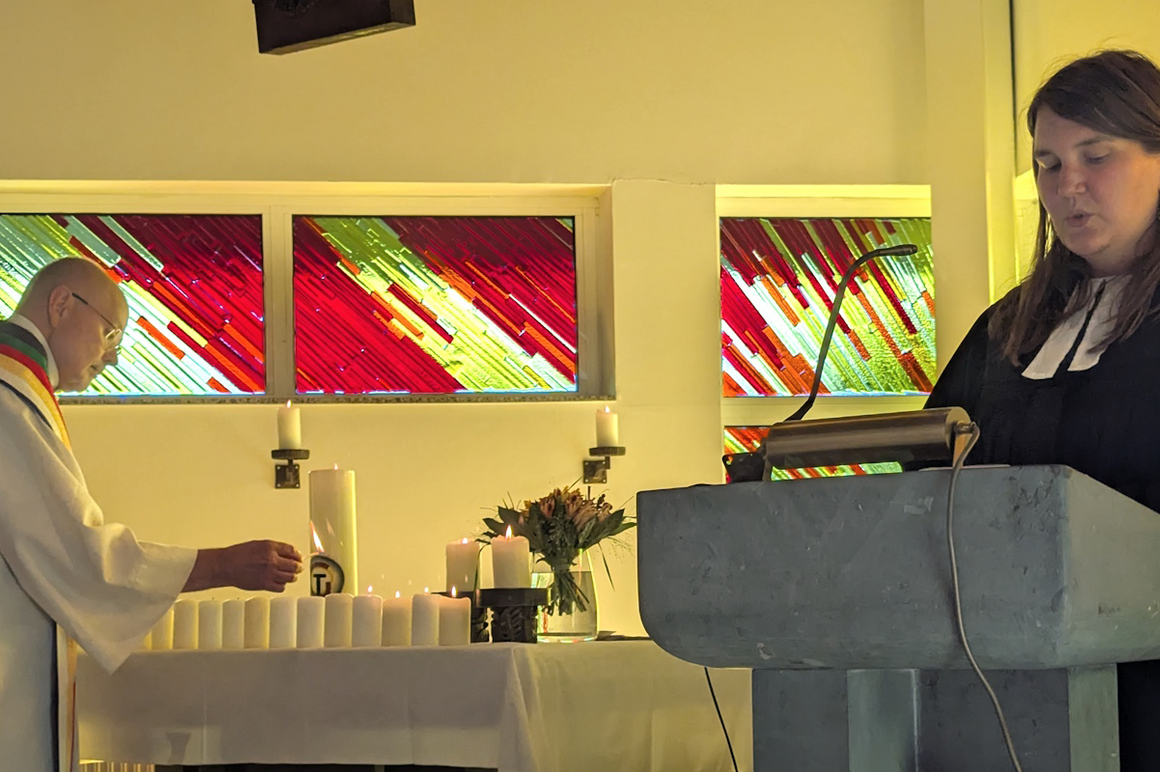 Eine männlich gelesene Person in weißem Talar und eine weiblich gelesene in schwarzem Talar in einer Kirche.