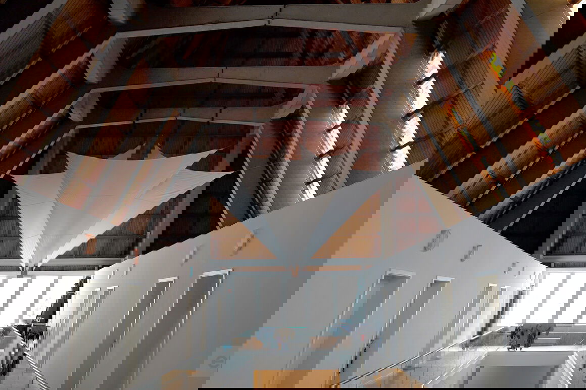 Blick in das Schiff einer Kirche, in das weiße Wände gezogen sind und Tücher unter der Holzdecke hängen.